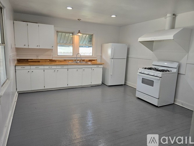 A kitchen with white cabinets and appliances is available for rent.