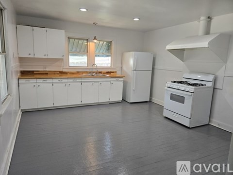 A kitchen with white cabinets and appliances is available for rent.