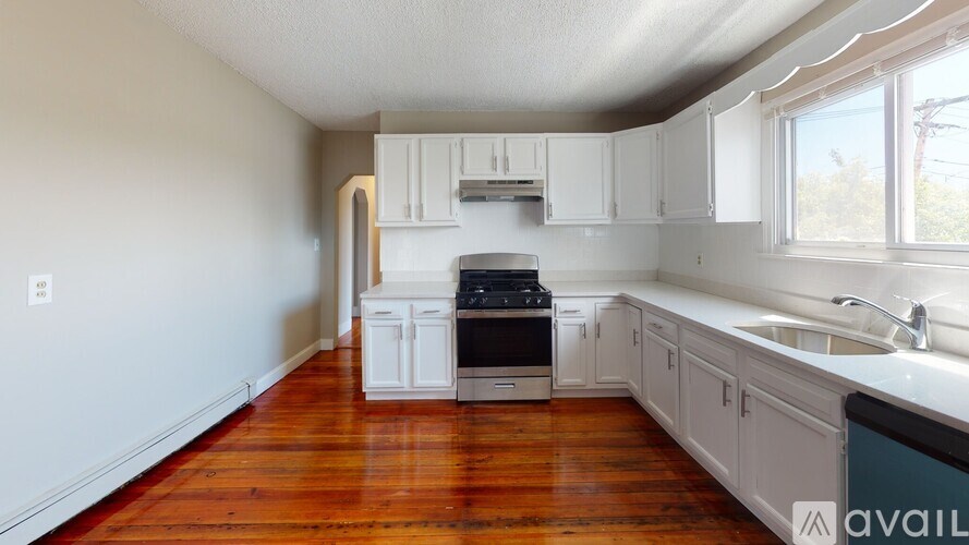 A kitchen with white cabinets and a wooden floor.