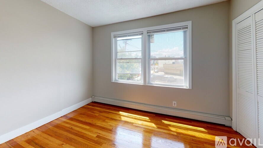 A room with wooden floors and a window overlooking a street.