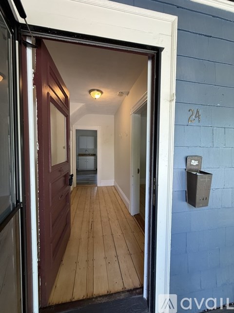 A hallway with a wooden floor and a door on the left.