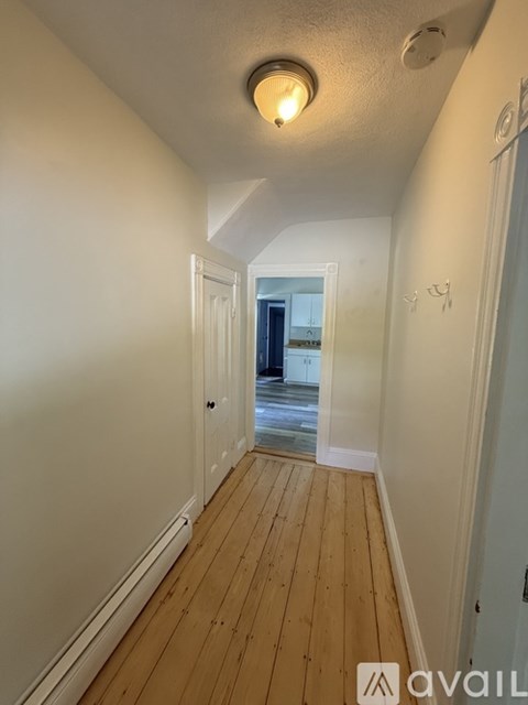 A long hallway with wood floors and white walls.