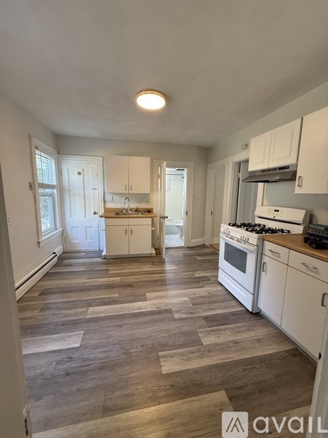 A kitchen with white cabinets and a wooden floor.