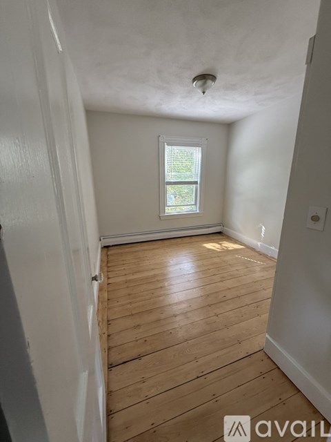 A room with wooden flooring and a window.