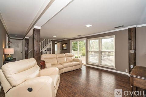 A living room with a row of white leather sofas and a wooden floor.