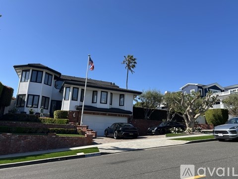A house with a flag on the roof and a car parked in front.