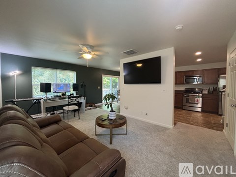 A living room with a brown leather couch and a flat screen TV mounted on the wall.