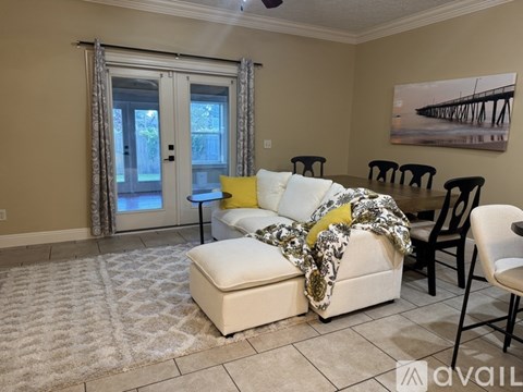 A living room with a white couch and a painting on the wall.