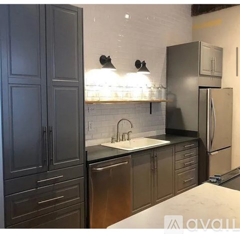 A kitchen with dark cabinets and a white backsplash.