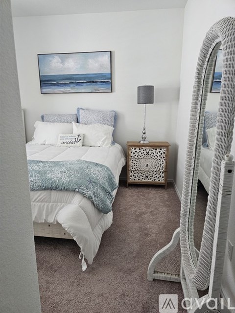 A white bedroom with a large bed and a painting on the wall.