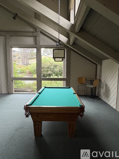 A pool table in a room with a hanging light fixture.