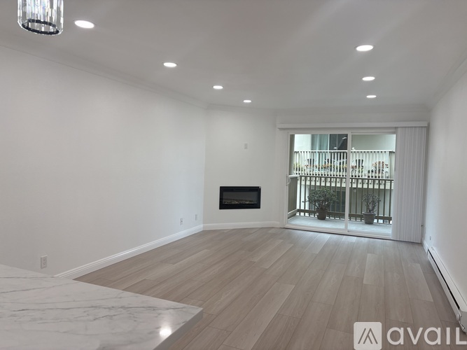 A spacious living room with a fireplace and a view of a balcony.
