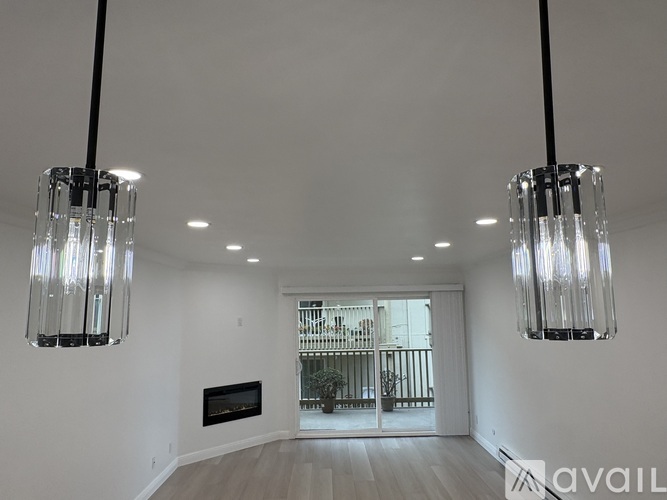A spacious room with a fireplace and two hanging lights.
