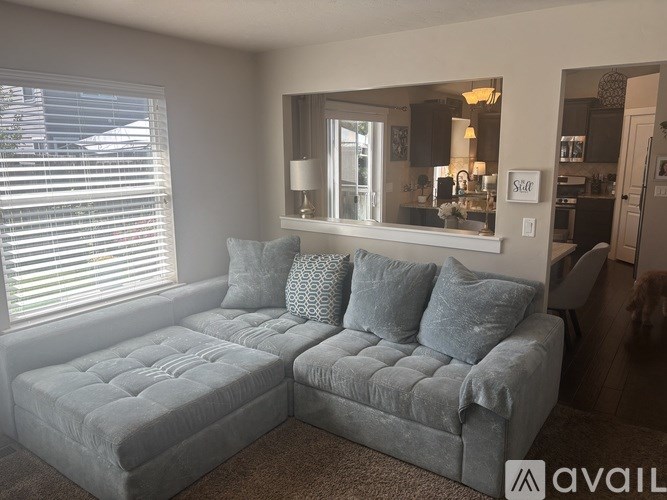 A living room with a grey couch and a mirror on the wall.
