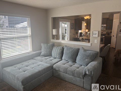 A living room with a grey couch and a mirror on the wall.