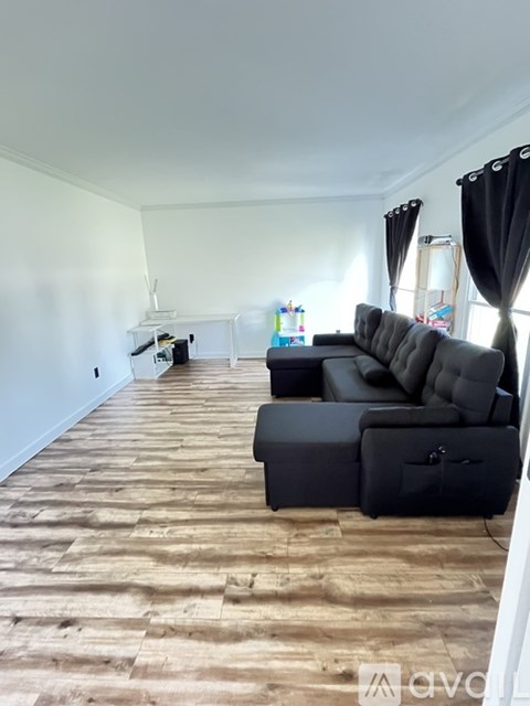 A living room with a grey couch and a wooden floor.