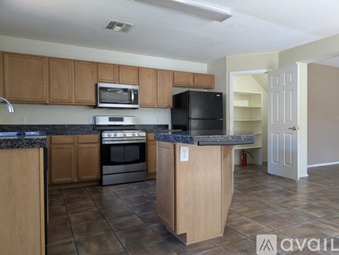A kitchen with wooden cabinets and a black refrigerator.