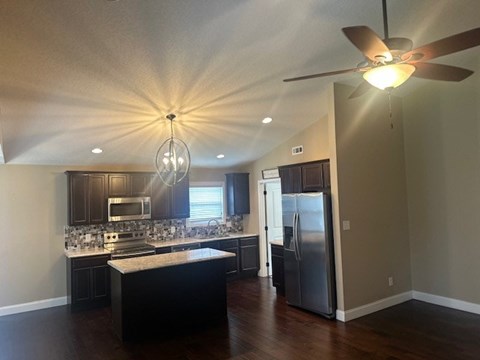 A kitchen with a black counter top and a ceiling fan.