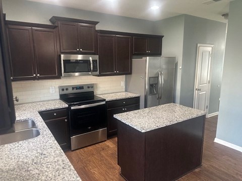 A kitchen with dark wood cabinets and granite countertops.