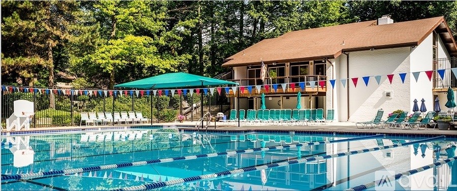 A large swimming pool in front of a house with a deck and sunshades.