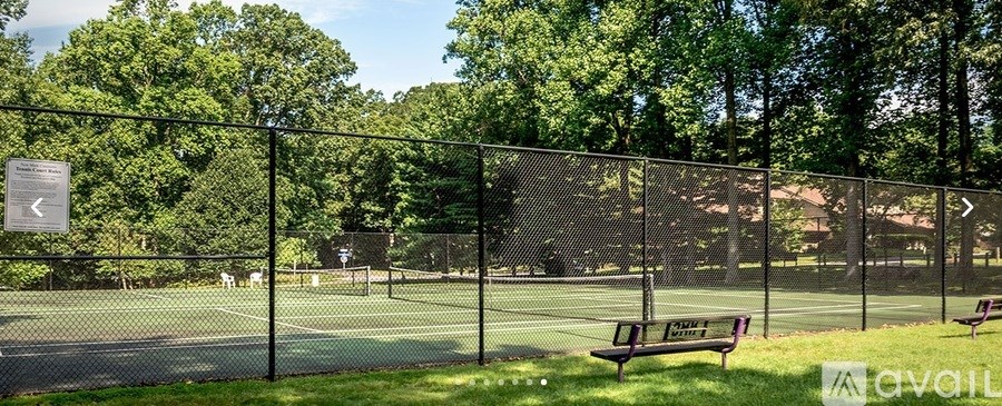 A tennis court surrounded by a fence with a sign on it.