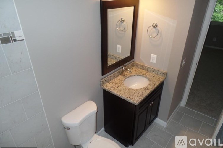 A bathroom with a toilet, sink, and mirror.
