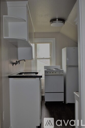 A small kitchen with white appliances and a black counter.