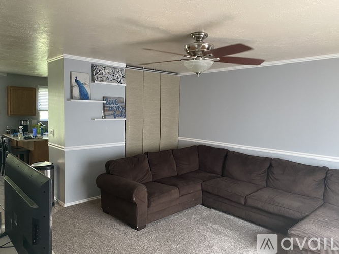 A living room with a brown couch and a ceiling fan.