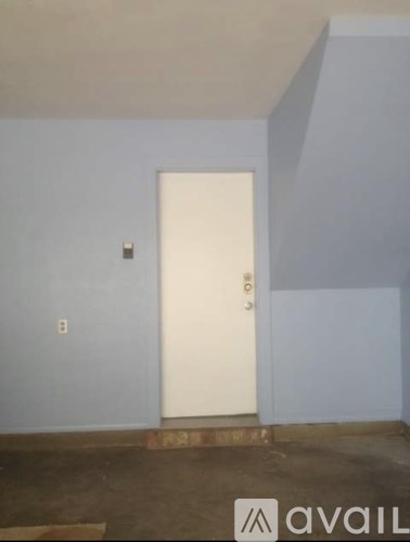 A white door is in the middle of a room with blue walls.