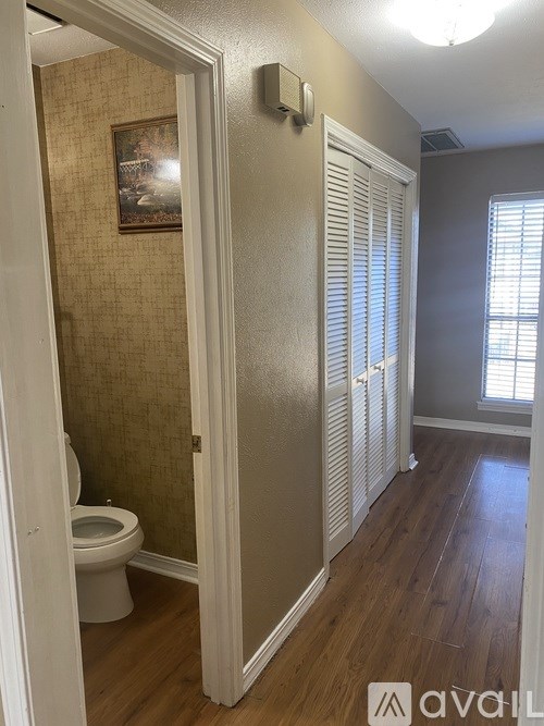 A bathroom with a toilet and a wooden floor.
