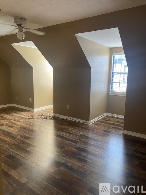 A room with wooden flooring and a ceiling fan.