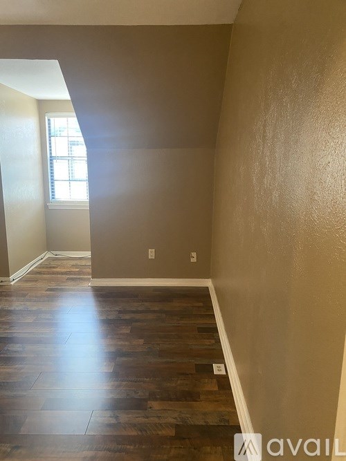 A room with wooden floors and a window letting in light.