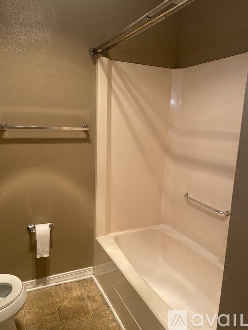 A bathroom with a toilet, a towel rack, and a bathtub.