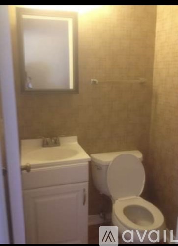 A white toilet in a small bathroom with a sink and mirror.