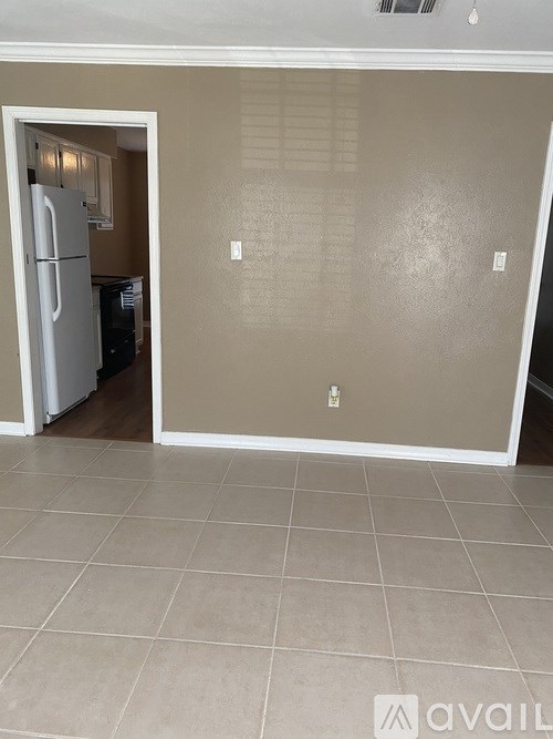 A kitchen with a white refrigerator and a doorway leading to another room.