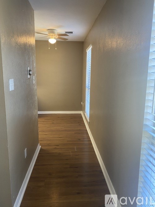 A long hallway with wood floors and a ceiling fan.