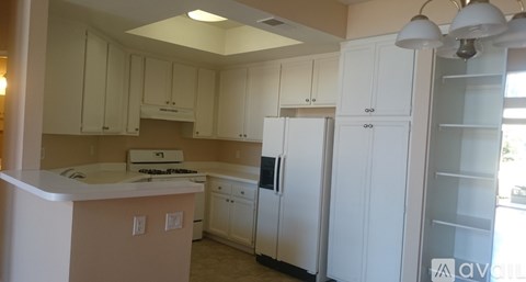 A kitchen with white cabinets and appliances.