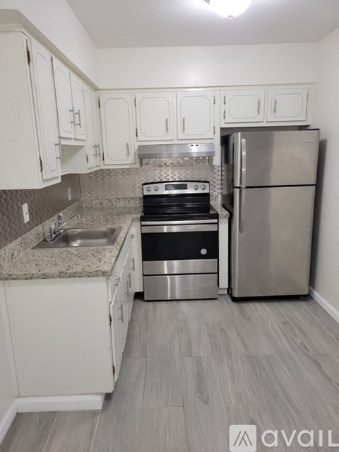 A kitchen with a stove, sink, and refrigerator.