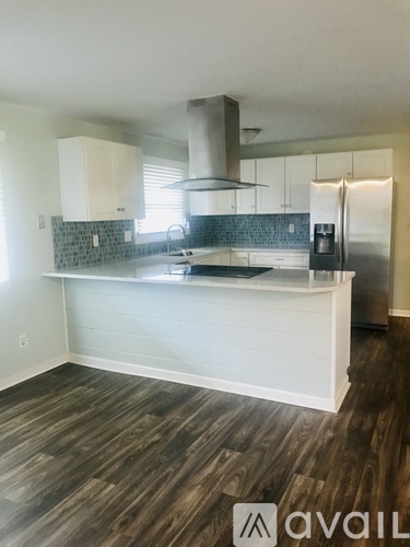 A kitchen with a white island and wooden floors.