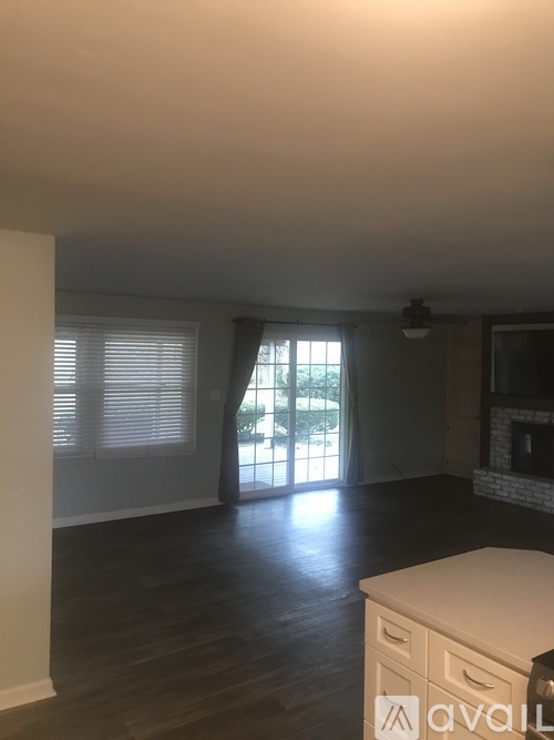 A room with wooden floors and a large window with blinds.