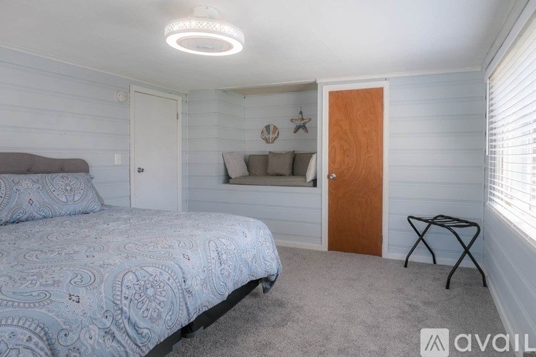 A bedroom with a bed, a chair, and a window with blinds.