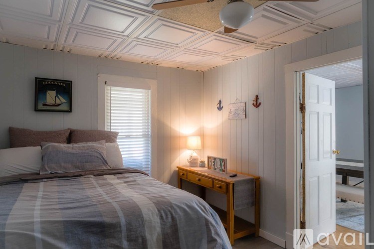 A bedroom with a bed, nightstand, and a painting on the wall.