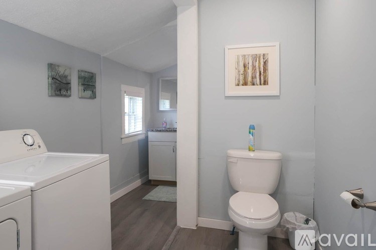 A bathroom with a toilet, washing machine, and a mirror.