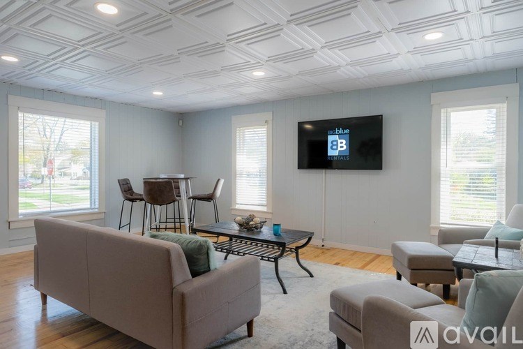 A living room with a couch, chairs, and a television mounted on the wall.