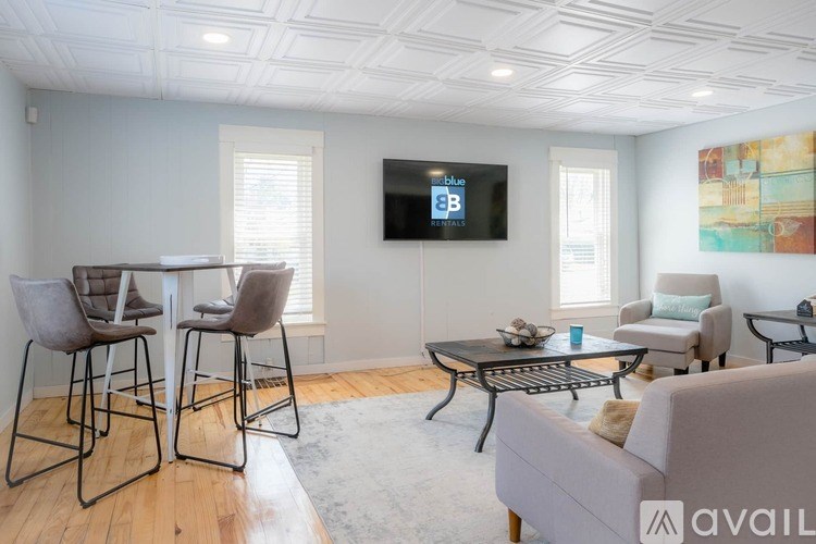 A living room with a grey couch, a black coffee table, and a television mounted on the wall.