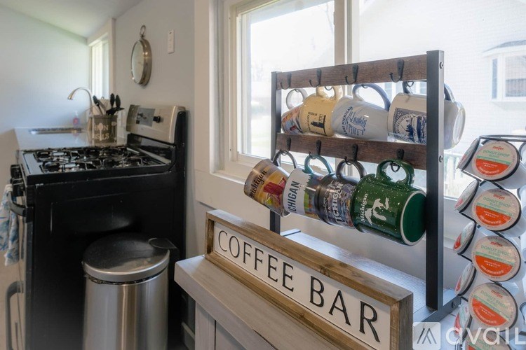 A coffee bar with a sign and a shelf with coffee mugs and cans.