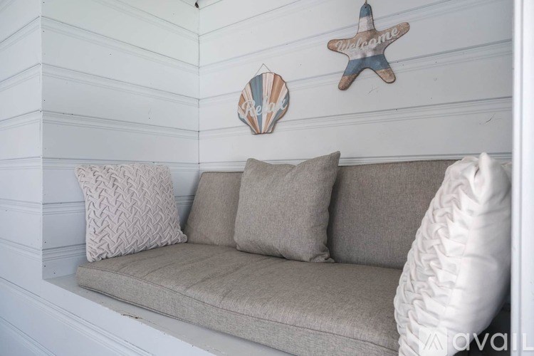 A beige couch with pillows and a starfish decoration on the wall.