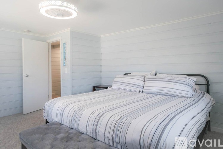 A bedroom with a bed, nightstand, and a door.