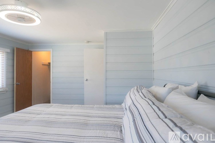 A bedroom with a bed, a window with blinds, and a door.