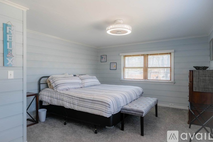 A bedroom with a bed, nightstand, and window.